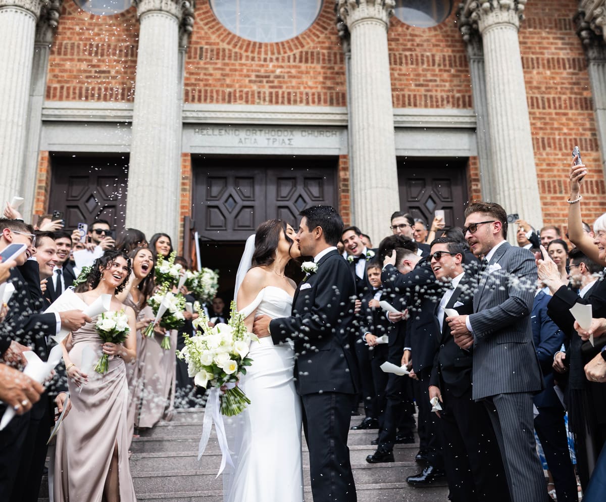 Newlyweds celebrating outside a church with their wedding party